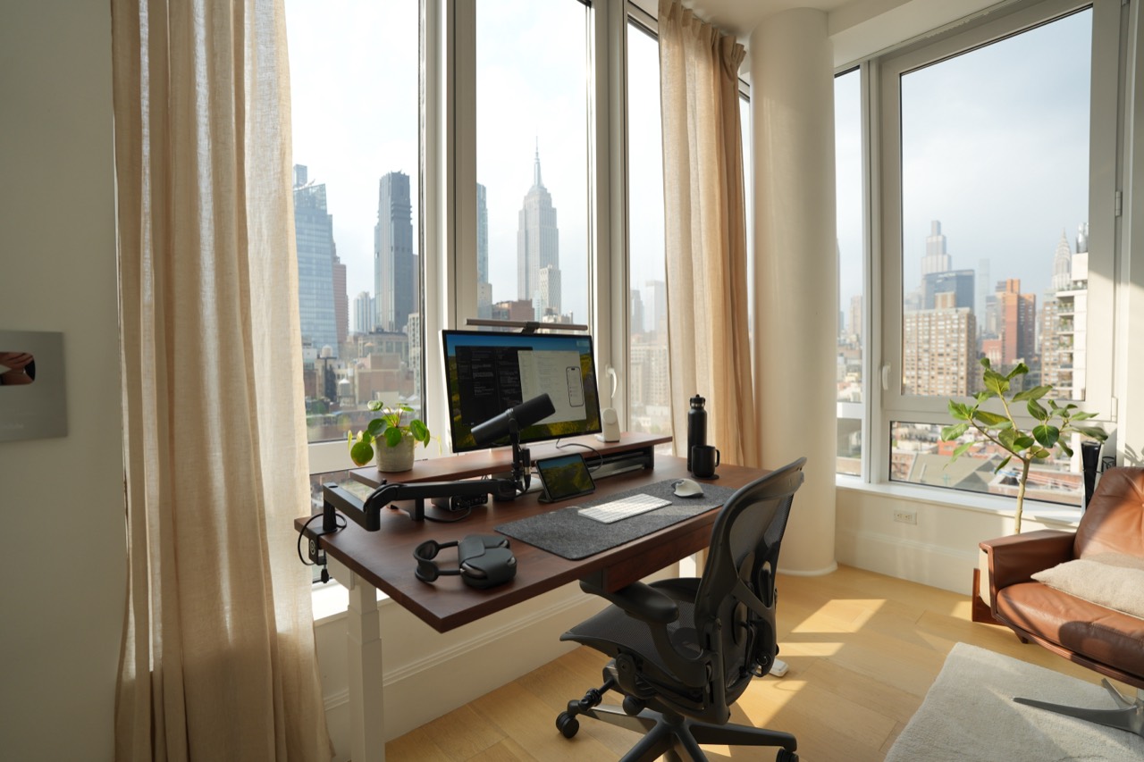 Walnut desk beside the corner windows, with an Aeron chair and lounge chair