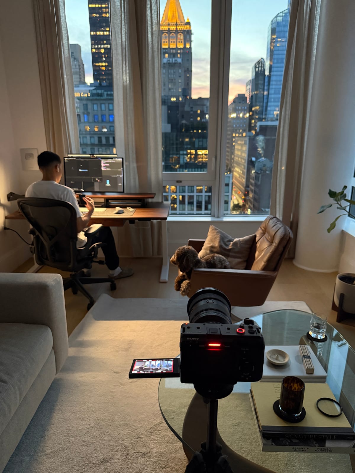 A camera filming the desk setup at dusk, with the dog on the lounge chair